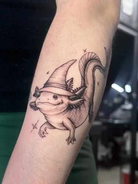 An axolotl in a wizard hat, in fine line and stipple.