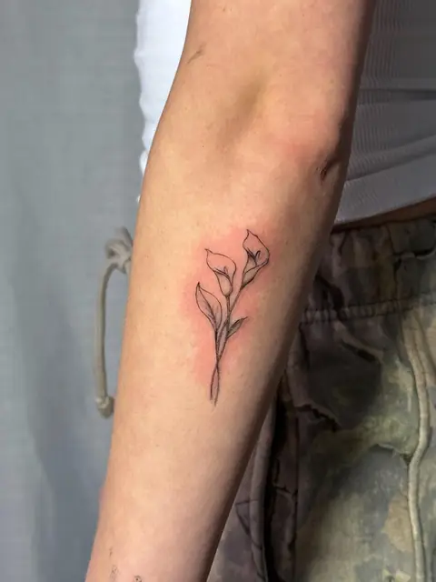 Two calla lilies in a single line, fresh on the forearm.