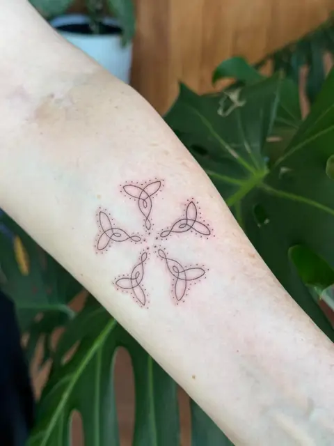 Four Celtic knots in a cross, ringed with a soft stipple.