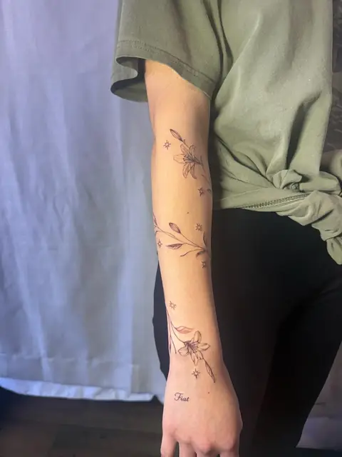 Lilies and stars running down the arm, with “Fiat” on the back of the hand.