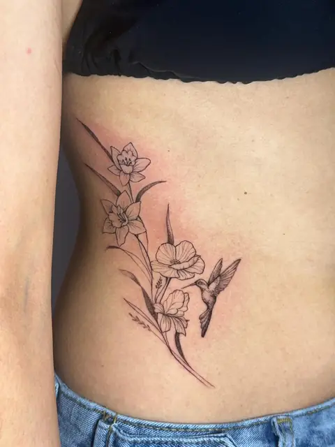 Daffodils and poppies on the rib, with a hummingbird leaning into the flowers.